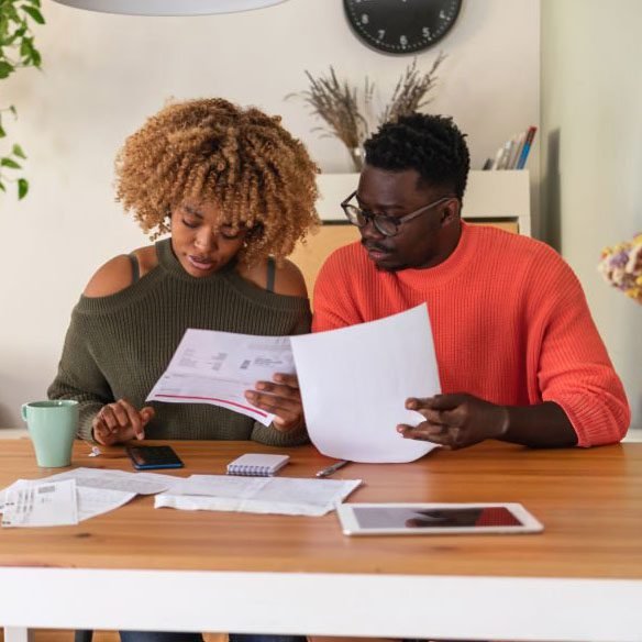 Couple reviewing household bills and financial documents together at a table.